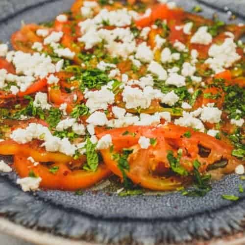 Tomatoes dressed in vinegar and oil with feta cheese and chopped mint