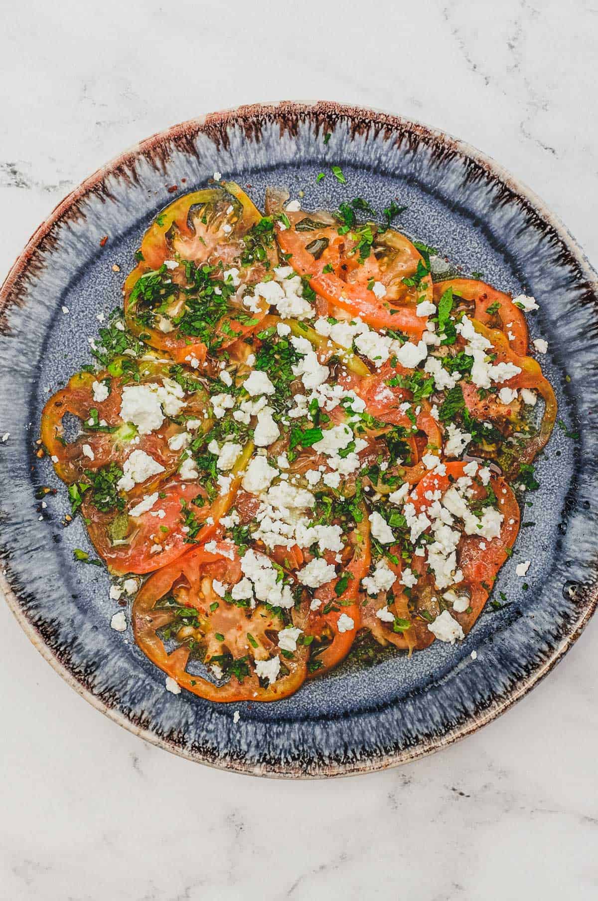 Tomatoes dressed in vinegar and oil with feta cheese and chopped mint