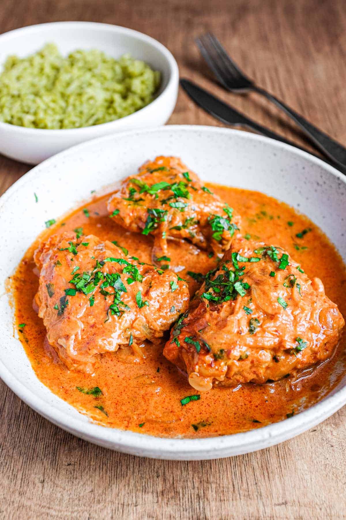 A bowl of Mexican chipotle chicken with a small bowl of green rice in the background