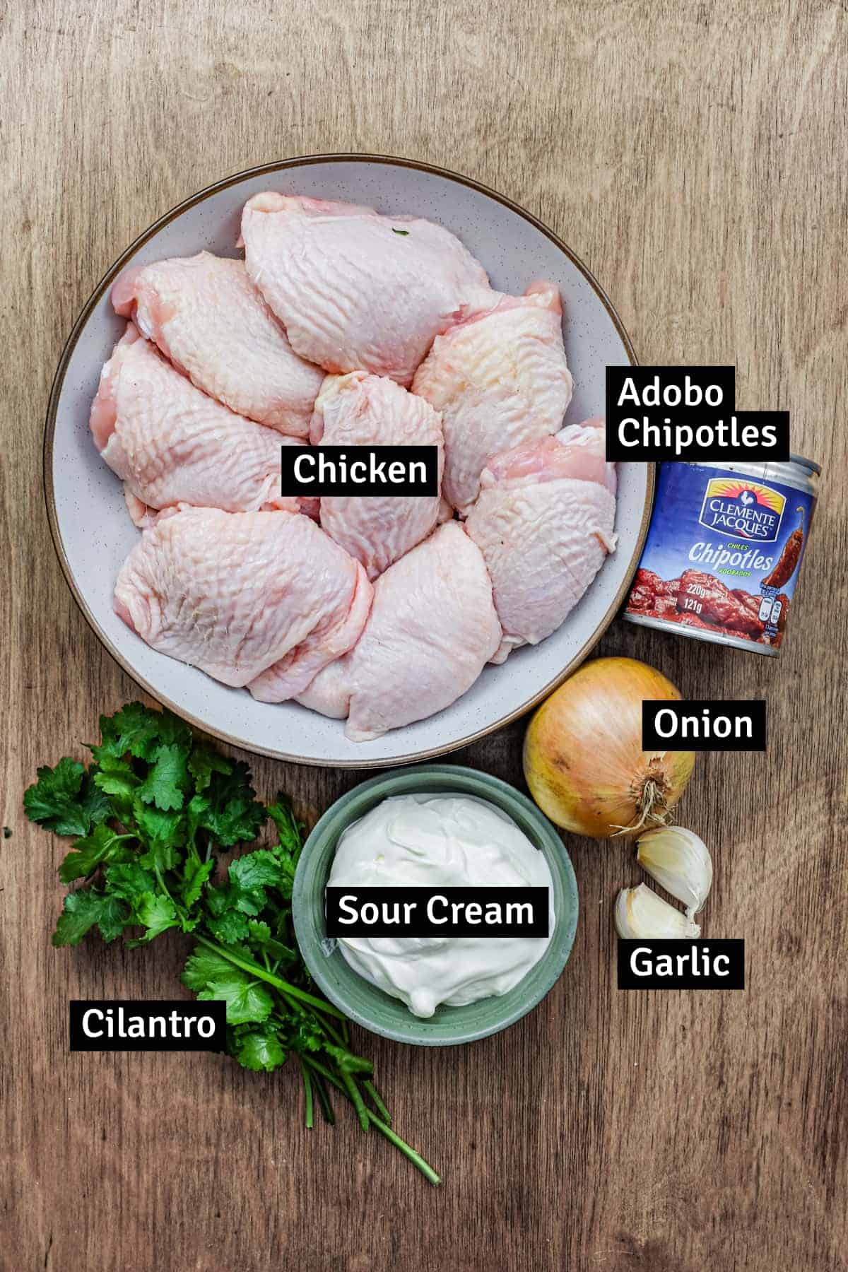 The ingredients for creamy chipotle chicken - chicken, sour cream, a small can of chipotle peppers in adobo sauce, onion, garlic and cilantro