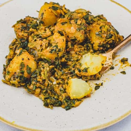 Saag aloo curry (Spinach & Potato) on a plate with a spoon