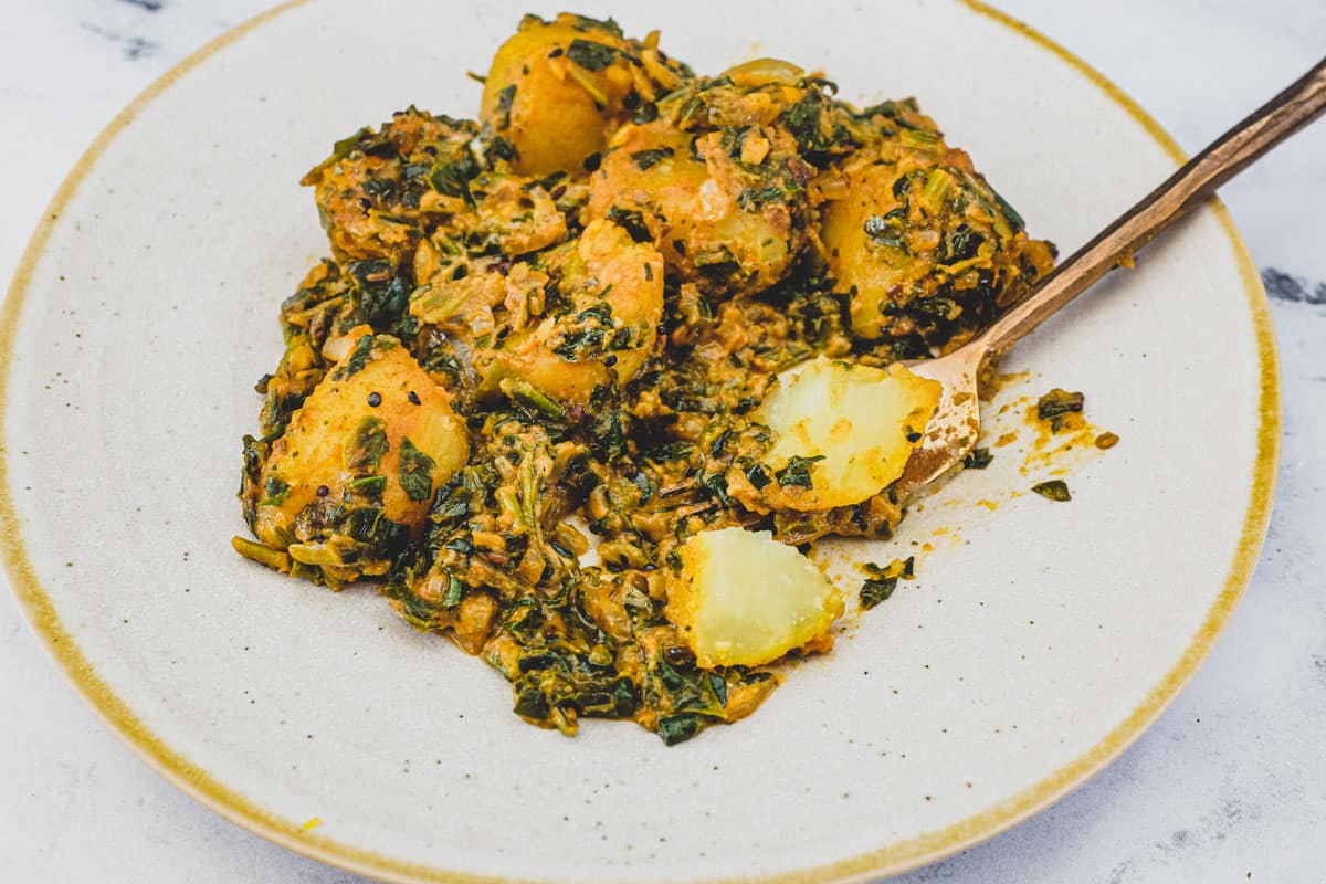 Saag aloo curry (Spinach & Potato) on a plate with a spoon