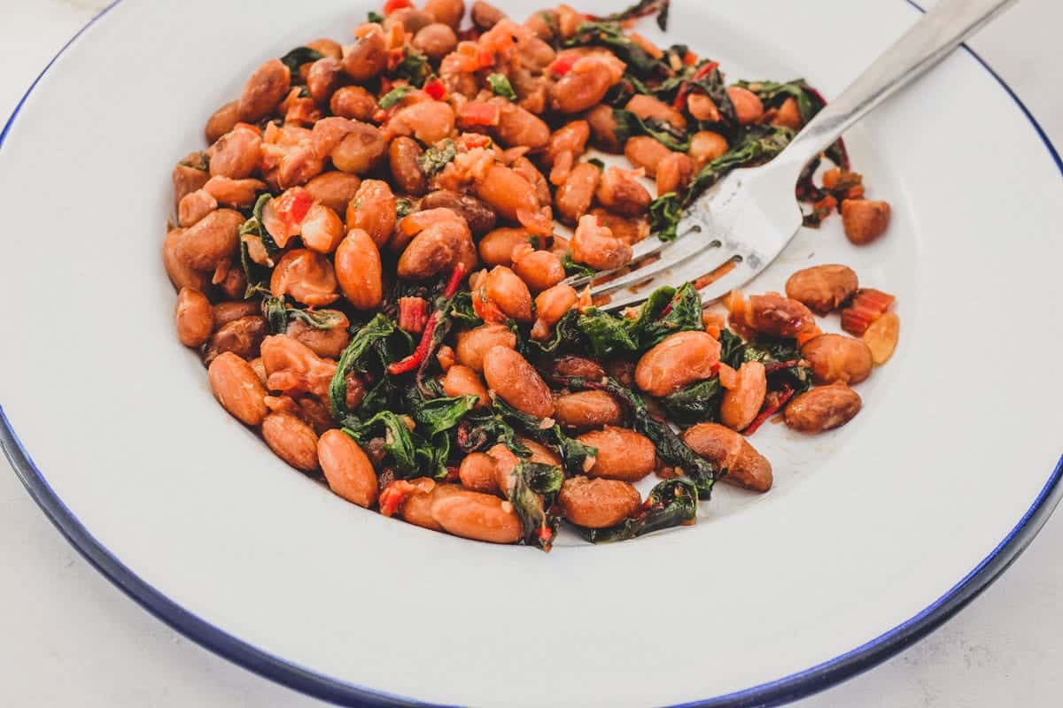 Borlotti beans cooked with chard (silverbeet) on a plate with a fork