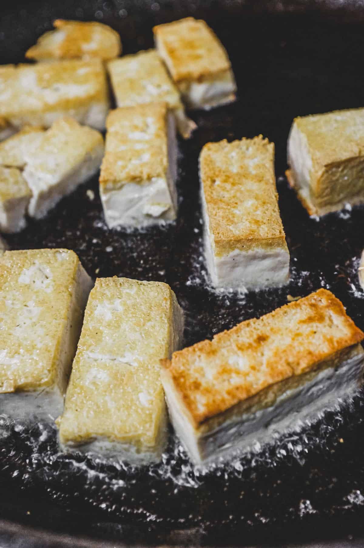 Tofu being fried in canola oil until crisp