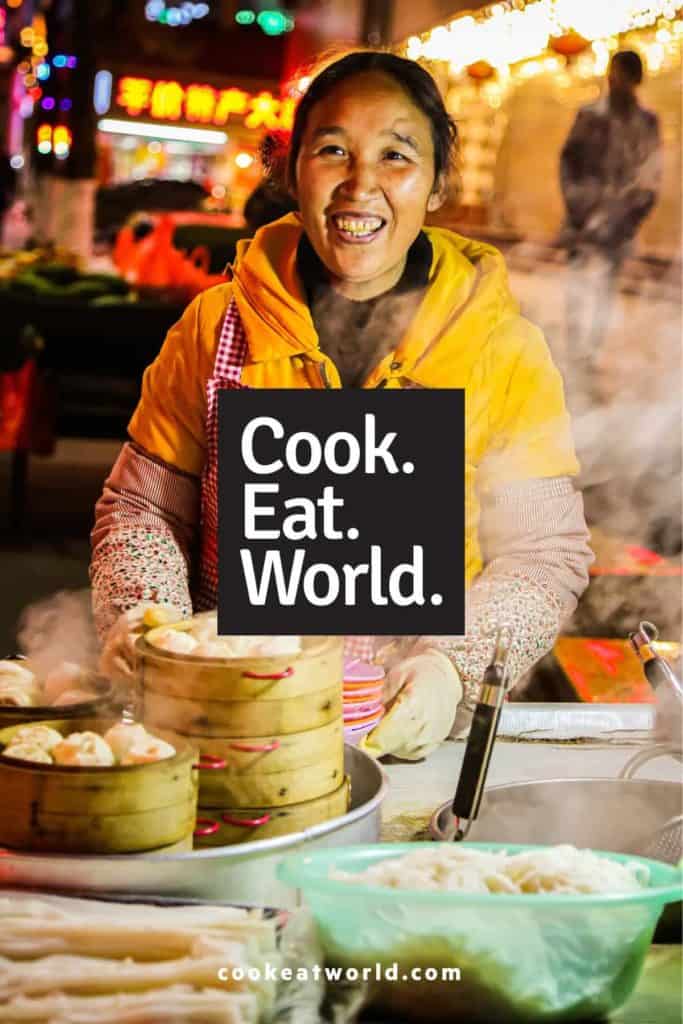 A chinese street vendor selling steamed dumplings with the logo for cook eat world dot com