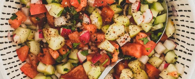 Cucumber, tomato & red onion are combined with a little cilantro and lime juice and served in a bowl as a chopped salad for Indian food.