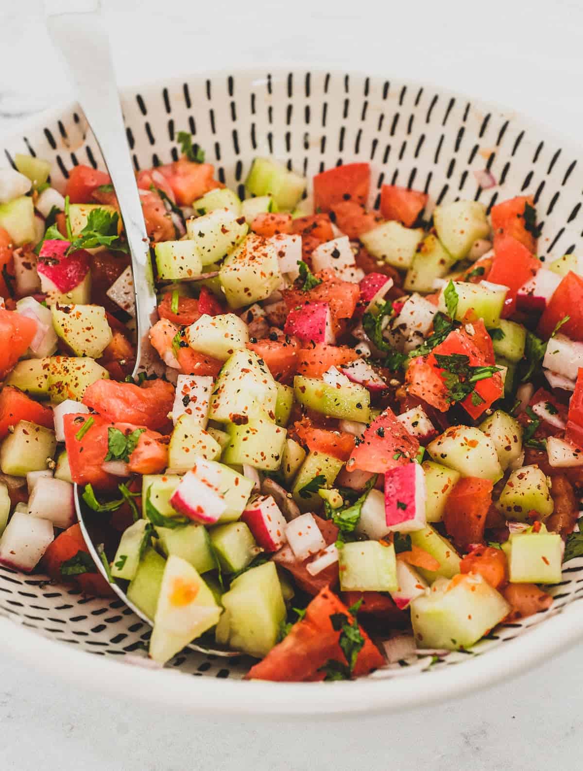 Cucumber, tomato & red onion are combined with a little cilantro and lime juice and served in a bowl as a chopped salad for Indian food.