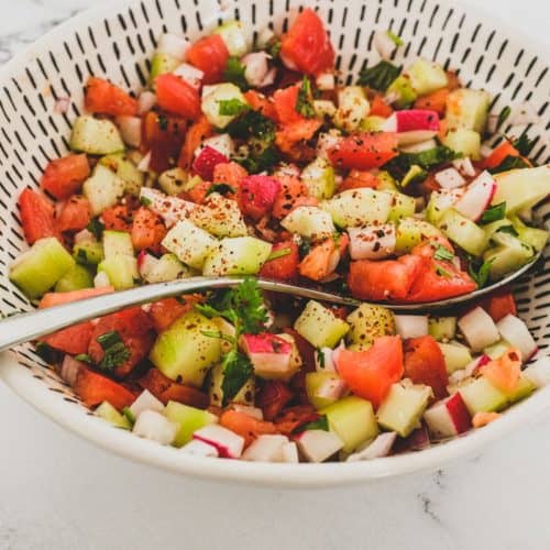 Cucumber, tomato & red onion are combined with a little cilantro and lime juice and served in a bowl as a chopped salad for Indian food.