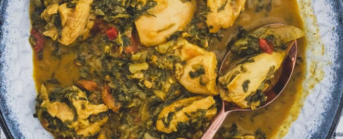 A bowl of chicken curry cooked with fenugreek leaves with a serving spoon