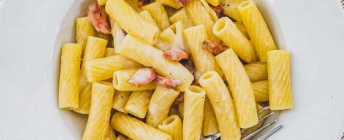 Rigatoni tubes in a bowl with Guanciale pork cheek and pecorino romano cheese