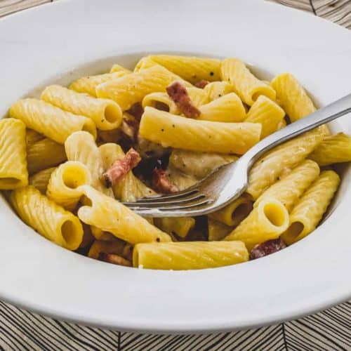 Rigatoni tubes in a bowl with Guanciale pork cheek and pecorino romano cheese