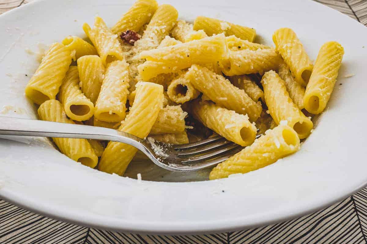 Rigatoni tubes in a bowl with Guanciale pork cheek and pecorino romano cheese