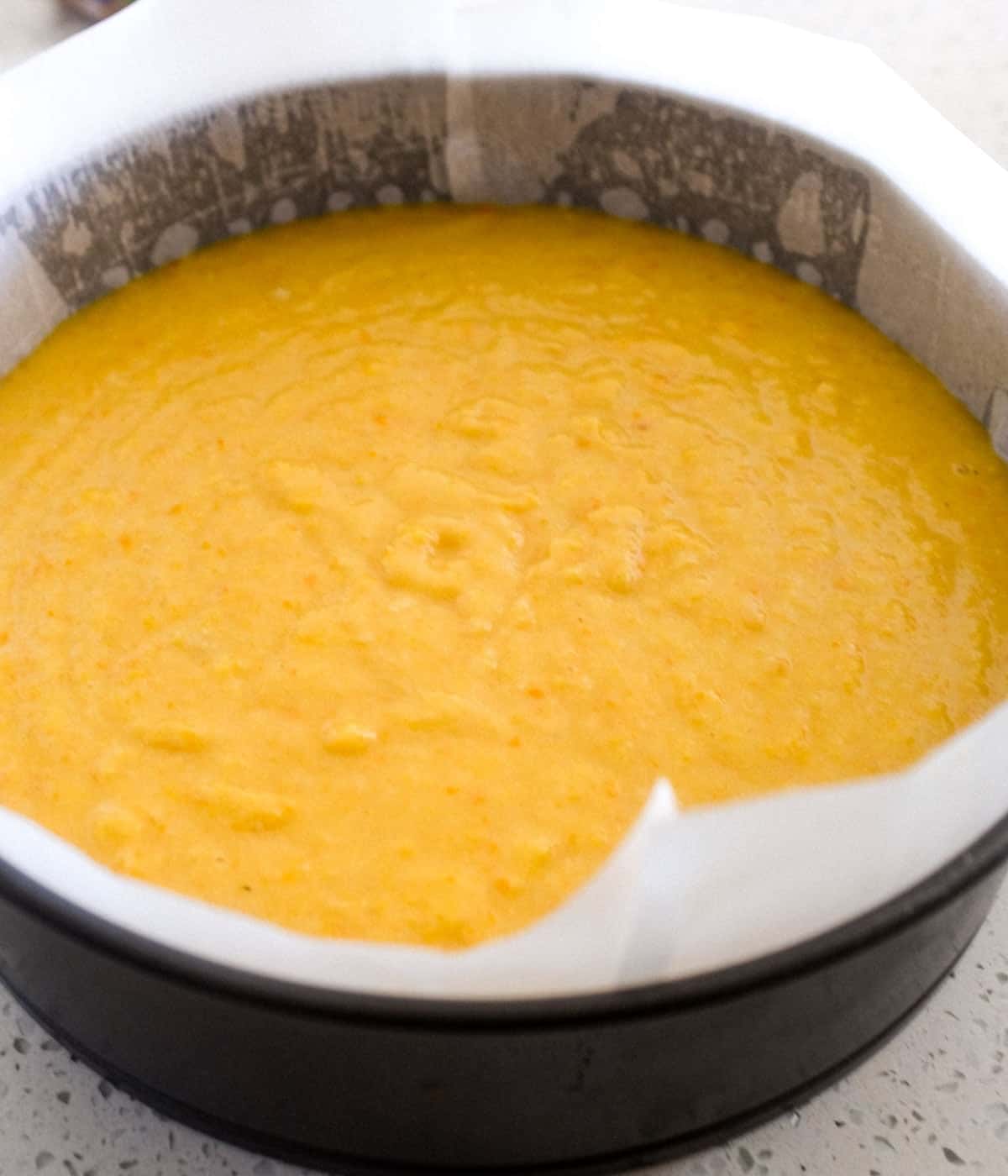 Flourless orange cake batter sits in a baking tin, ready to be baked