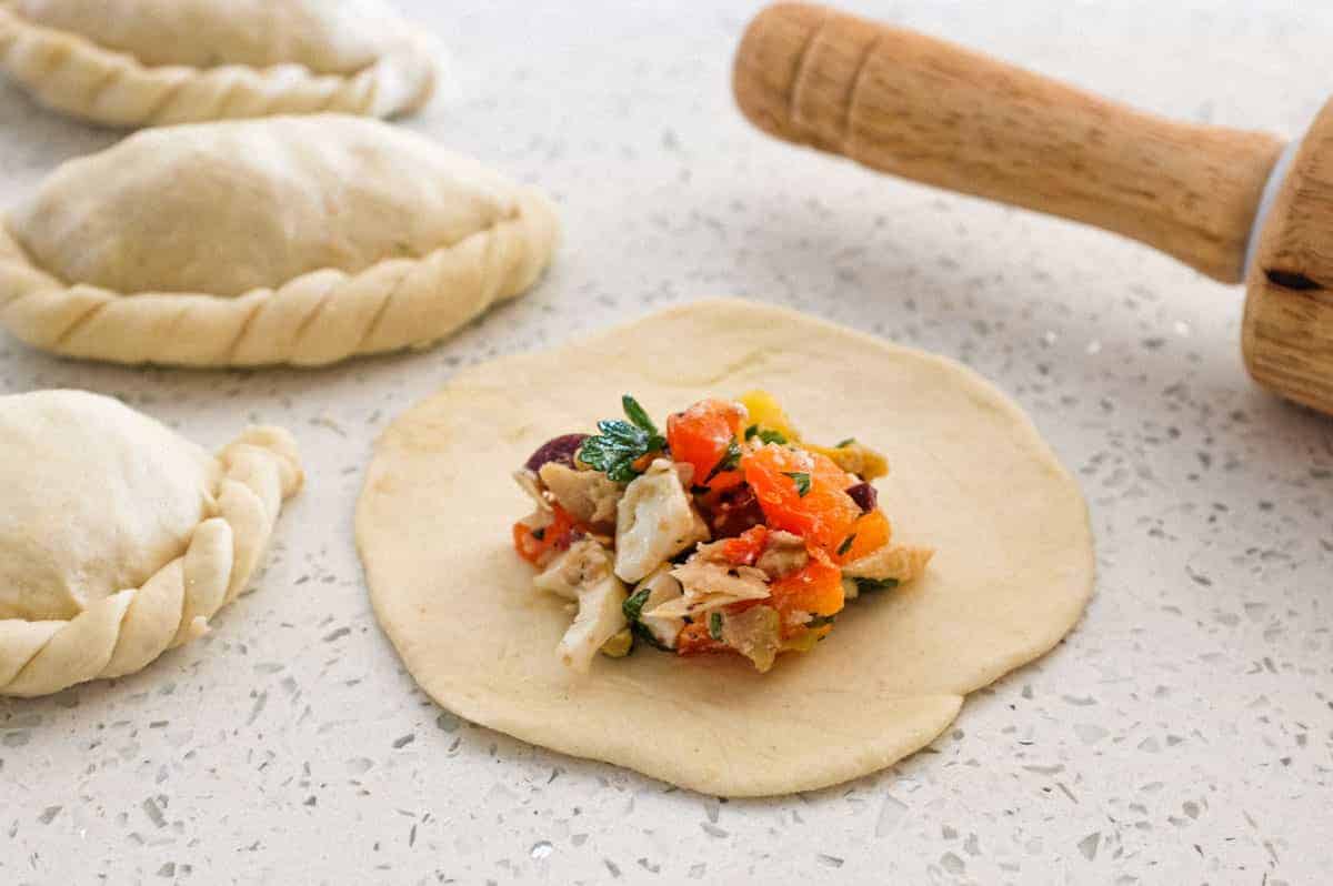 Panzerotti dough circle with the filling on top, small folded panzerotti surround the non folded version