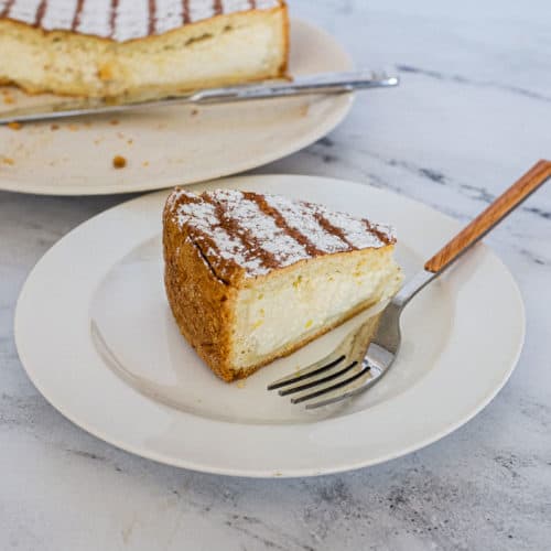 A slice of Italian Ricotta pie with the remaining pie in the background