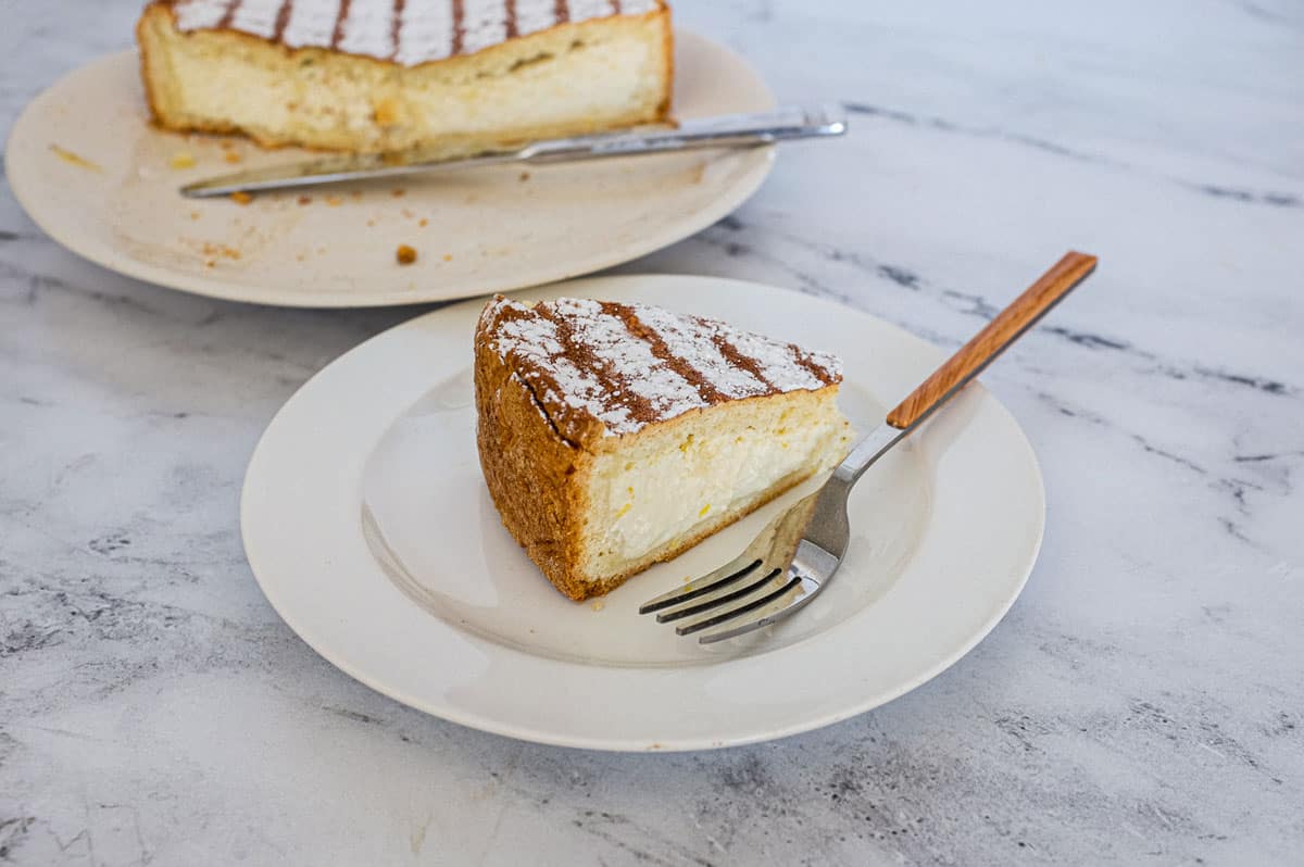 A slice of Italian Ricotta pie with the remaining pie in the background