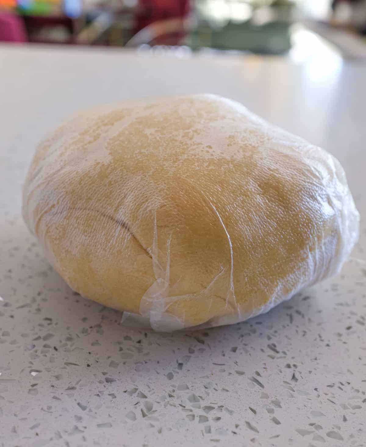 A ball of sweet pastry dough wrapped in plastic for Italian Ricotta Pie