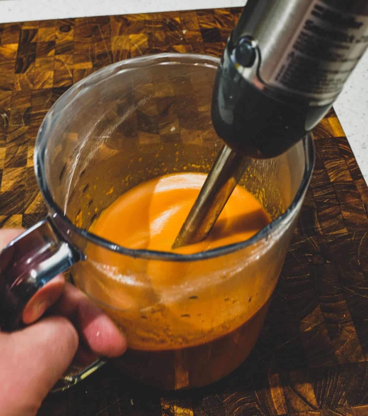 Blending together onion, garlic, sherry and smoked paprika using an immersion blender.