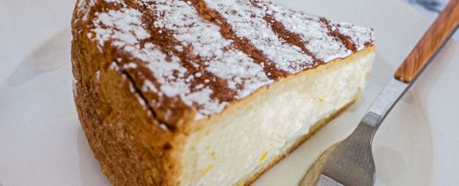 A slice of Italian ricotta pie sits on a plate with the remaining pie in the background.