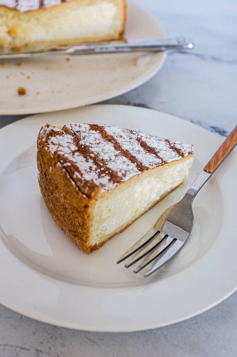 A slice of Italian ricotta pie sits on a plate with the remaining pie in the background.