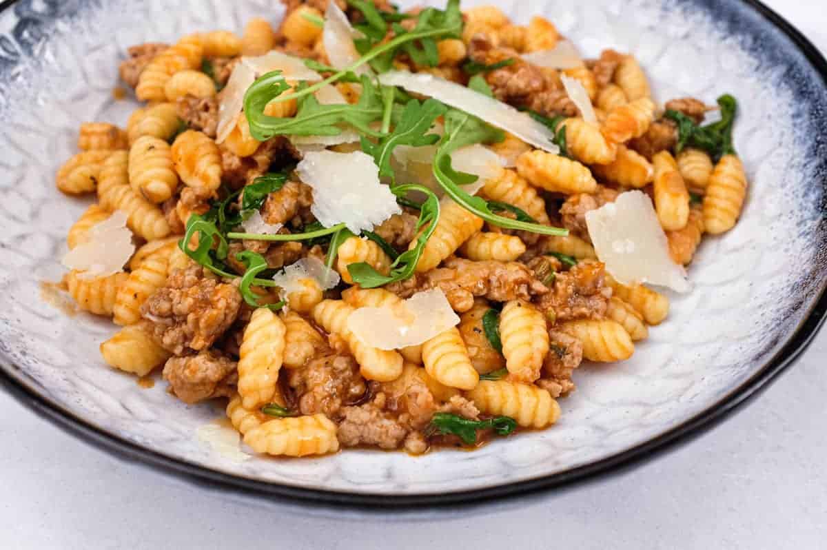 A plate of Malloreddus (Gnocchetti Sardi) with Sausage Ragù with arugula and Pecorino Sardi Cheese