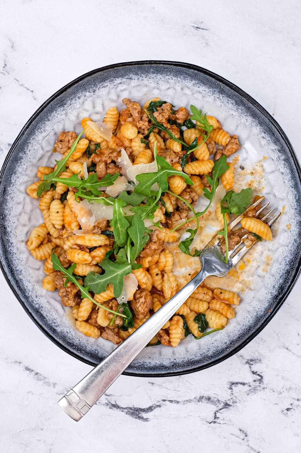 A plate of Malloreddus (Gnocchetti Sardi) with Sausage Ragù with arugula and Pecorino Sardi Cheese