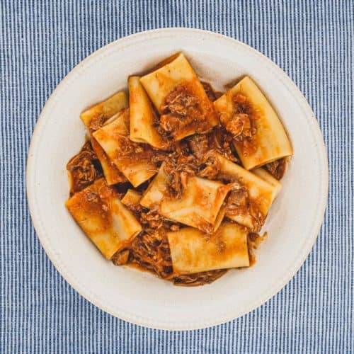 A bowl of paccheri pasta with a rich Neapolitan ragù sauce