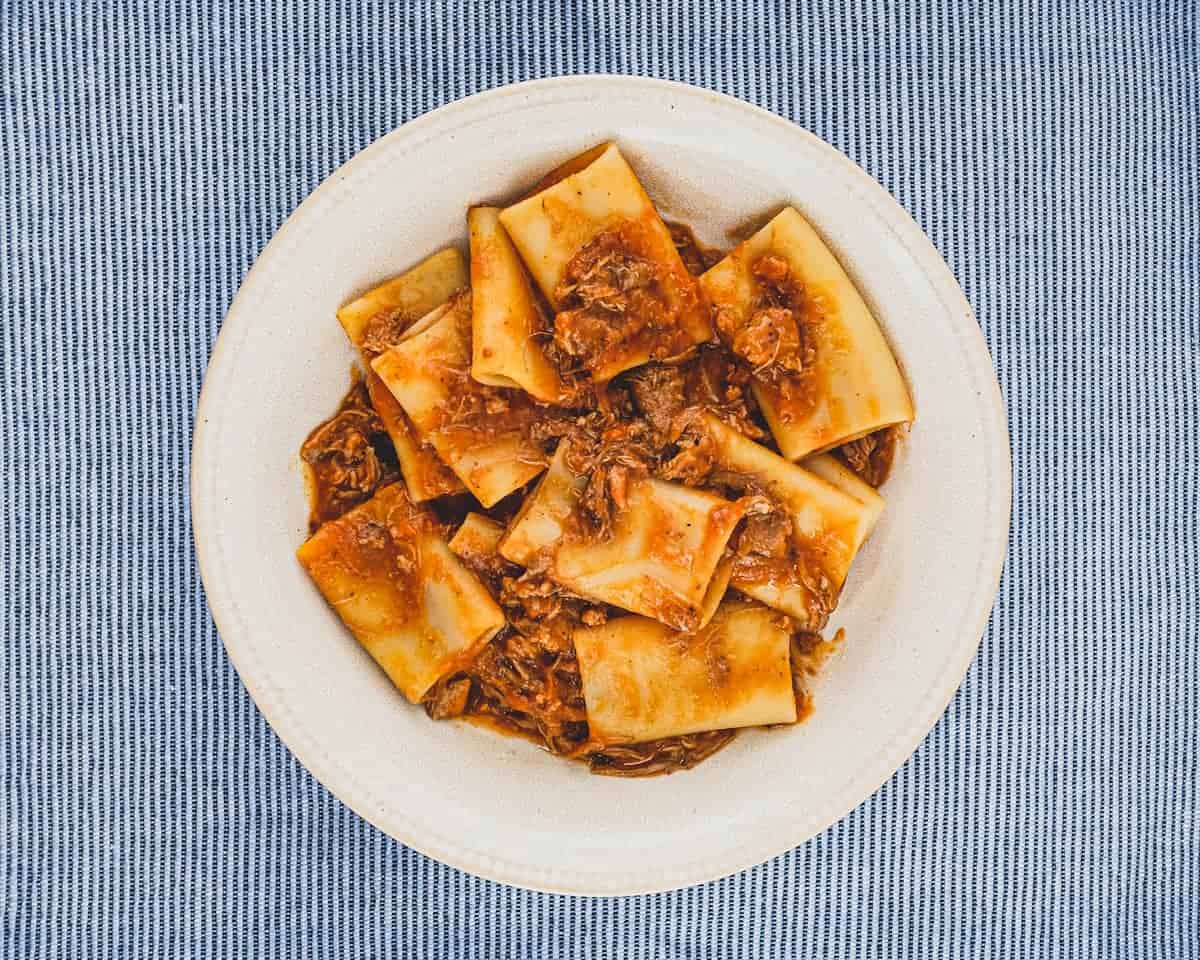 A bowl of paccheri pasta with a rich Neapolitan ragù sauce