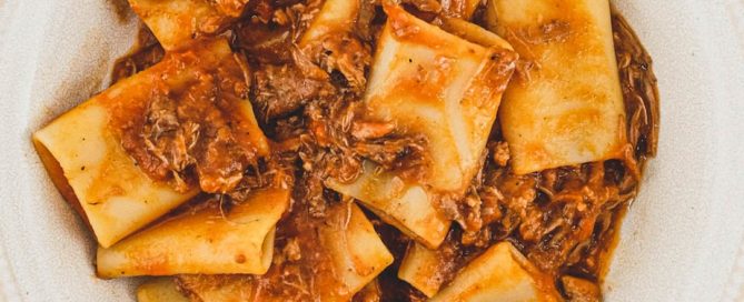 A bowl of paccheri pasta with a rich Neapolitan ragù sauce