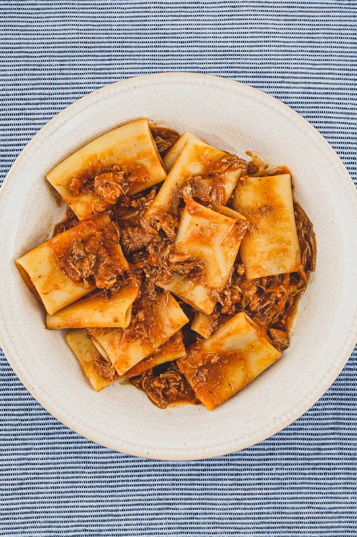 A bowl of paccheri pasta with a rich Neapolitan ragù sauce