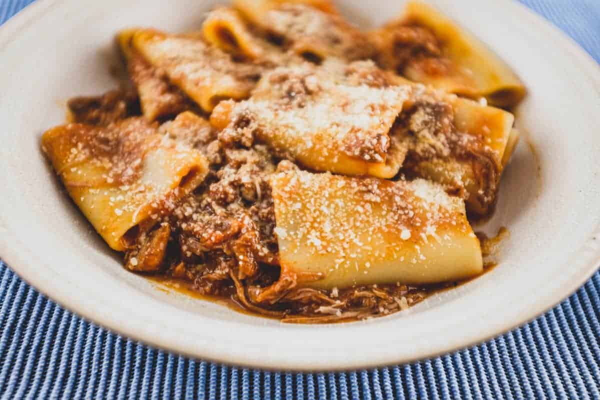 A bowl of paccheri pasta with a rich Neapolitan ragù sauce