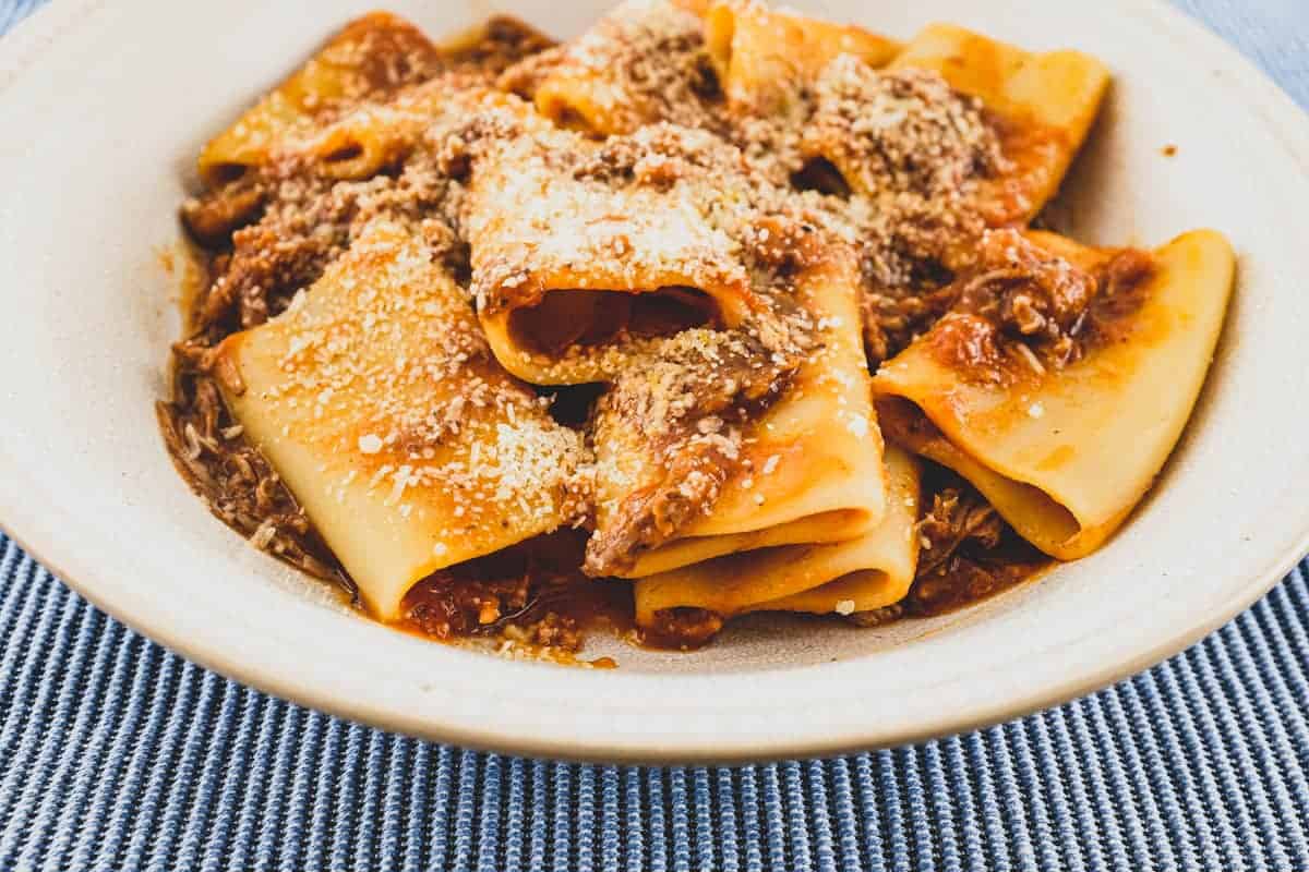 A bowl of paccheri pasta with a rich Neapolitan ragù sauce