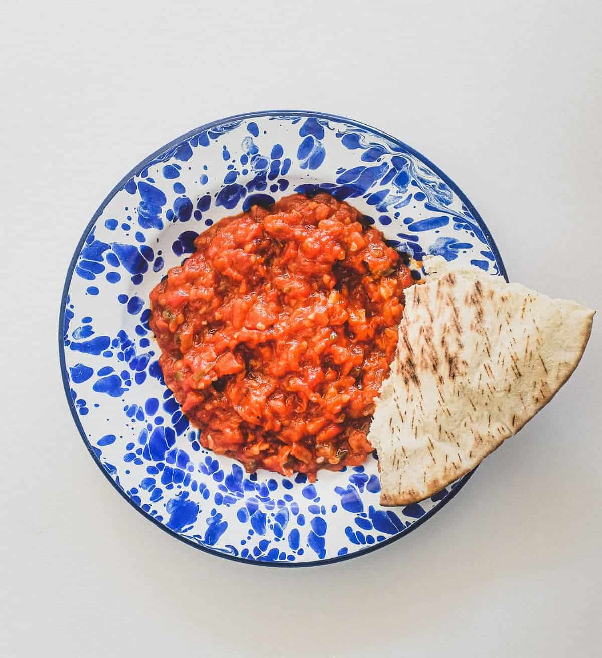 Moroccan Matbucha in a vibrant blue meze bowl. Peppers and tomatoes are stewed to a thick, tangy paste.