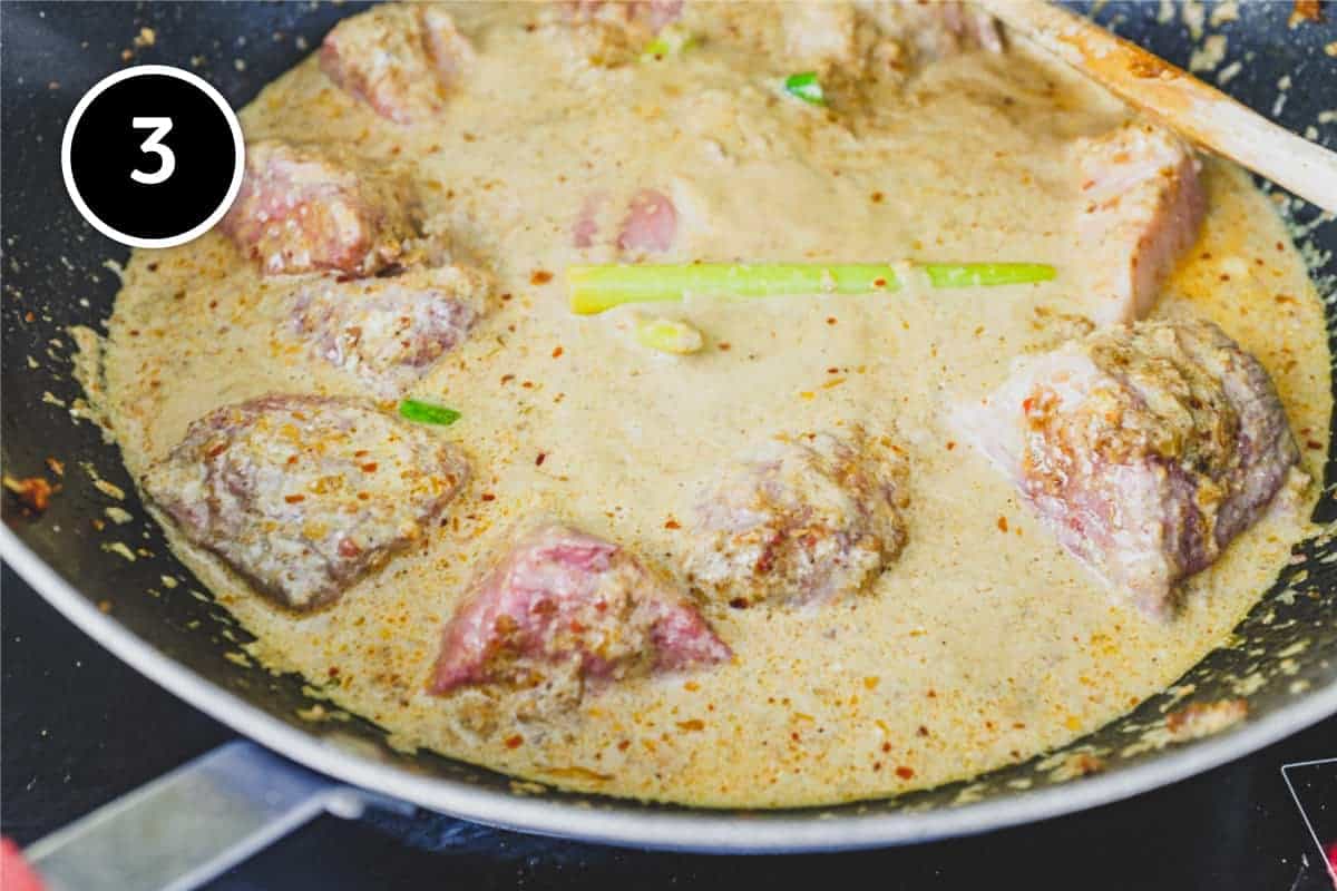 Beef rendang simmering in a pan