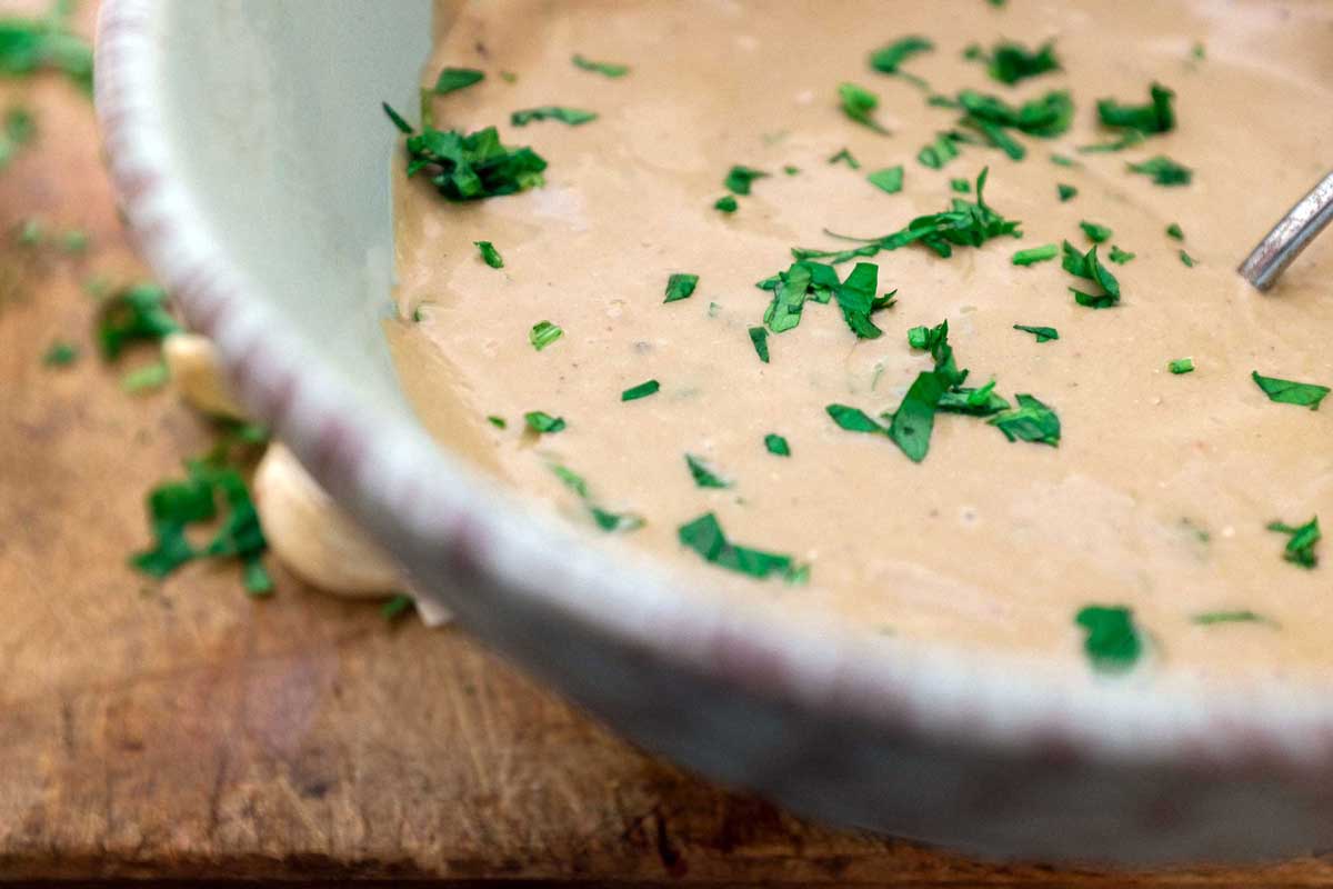 A bowl of Anchovy Sauce, scattered with fresh parsley.