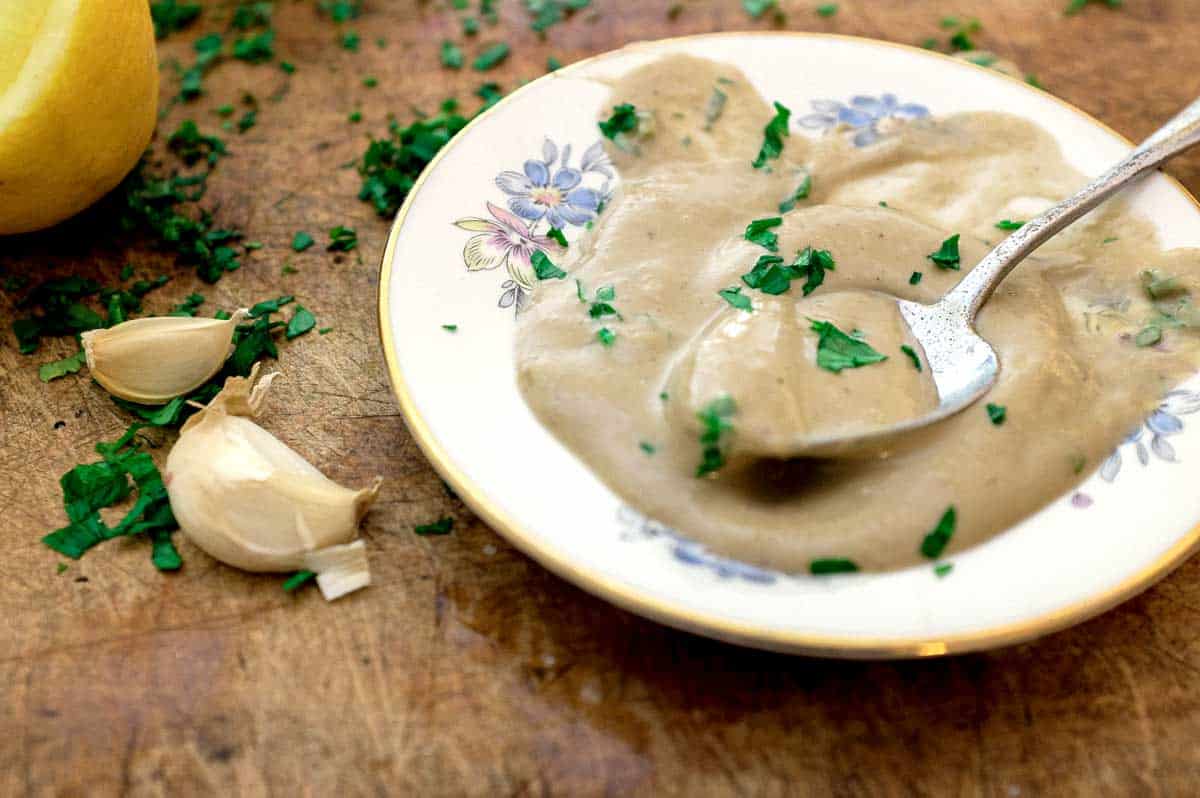 A small pate of Anchovy Sauce with a spoon, scattered with parsley.