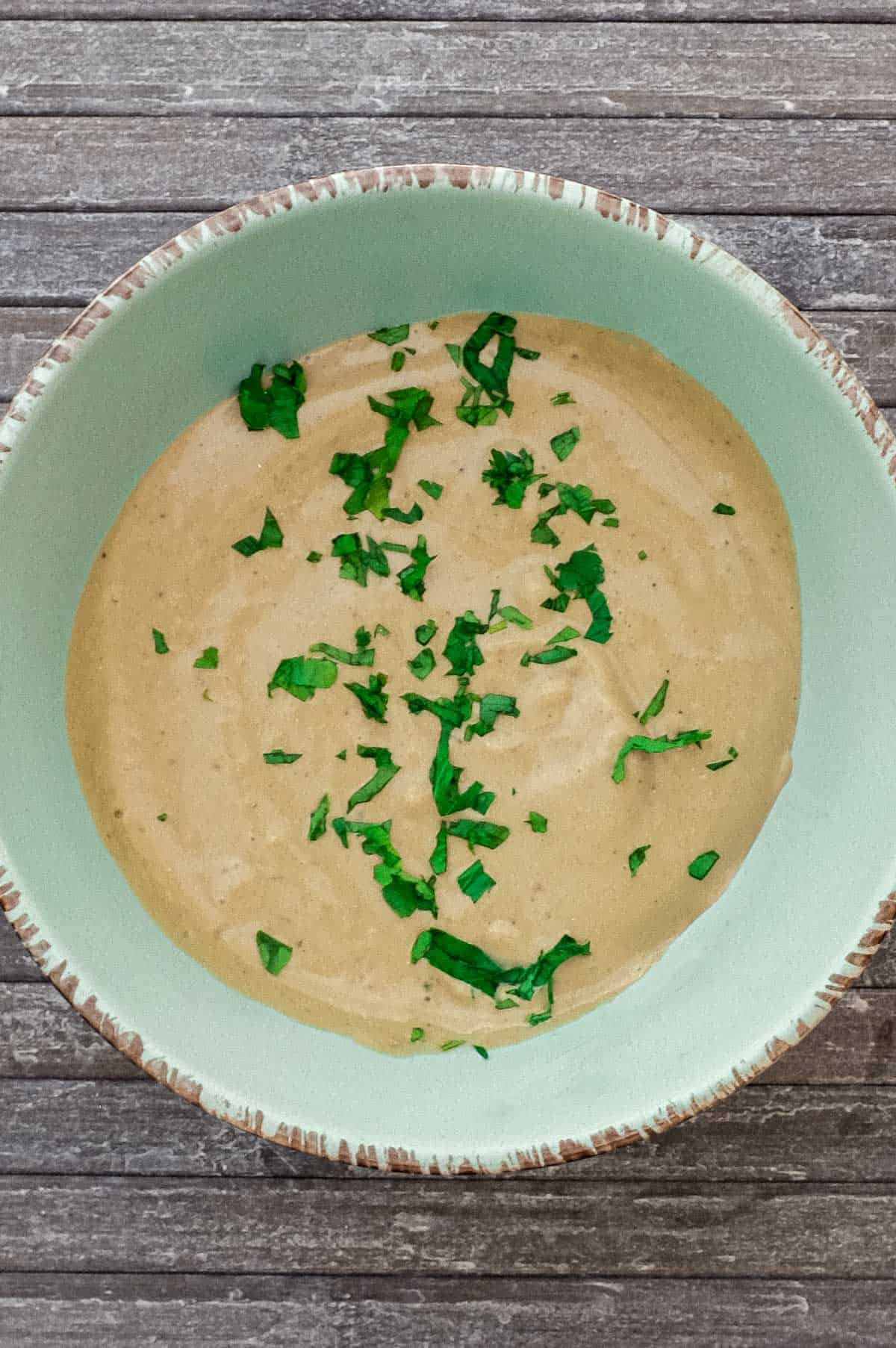 A bowl of Anchovy sauce scattered with fresh parsley.