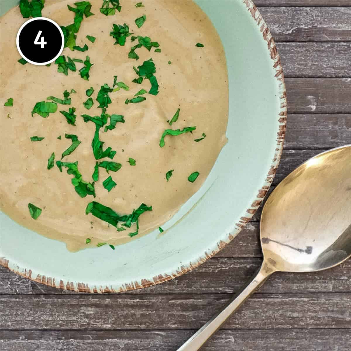 A bowl of Anchovy Sauce with a spoon, scattered with fresh parsley.