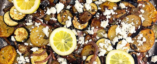 A platter of Greek Roasted Vegetables called Briam scattered with feta cheese and lemon slices