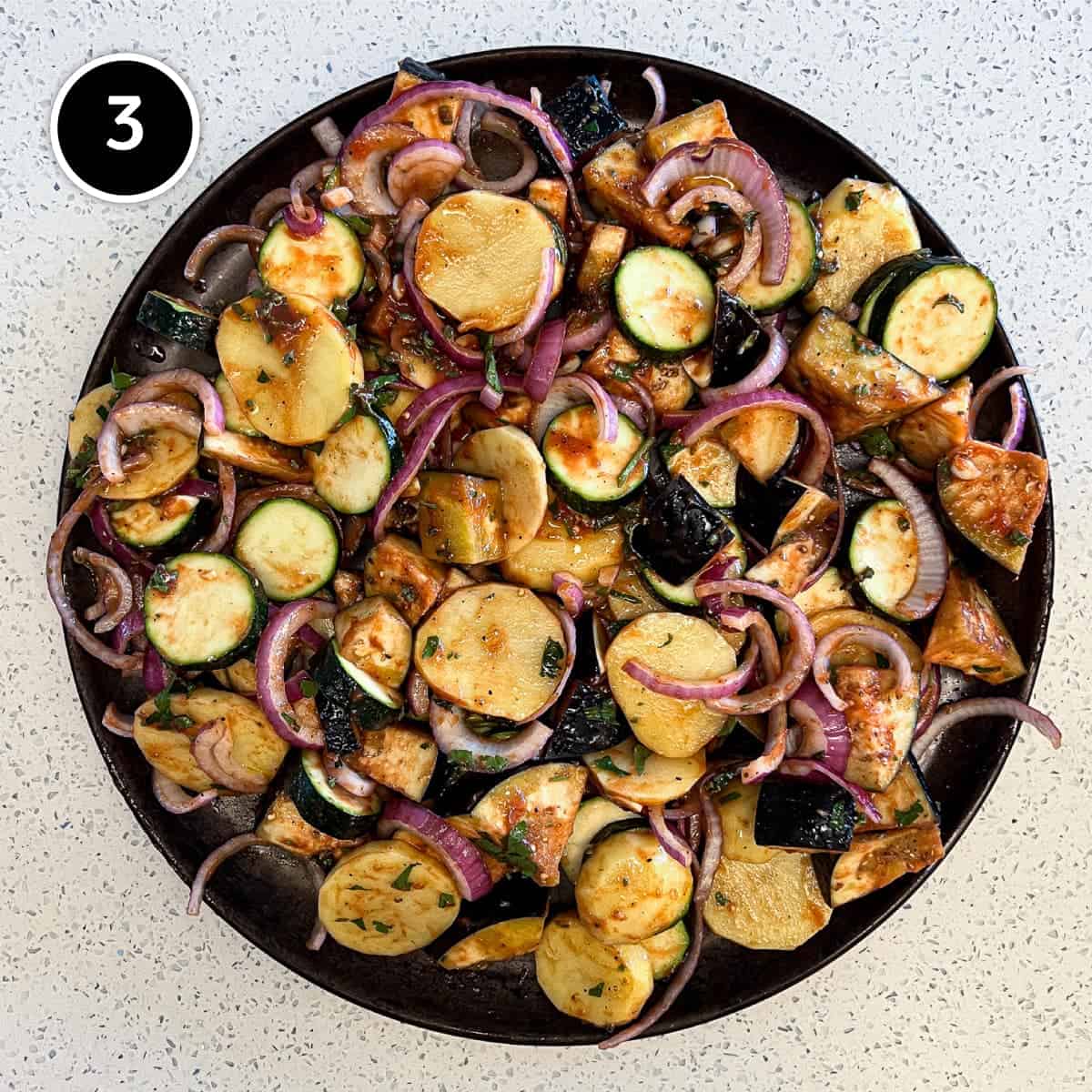 Spreading the ingredients for Greek Briam (Roasted vegetables on a large baking sheet.