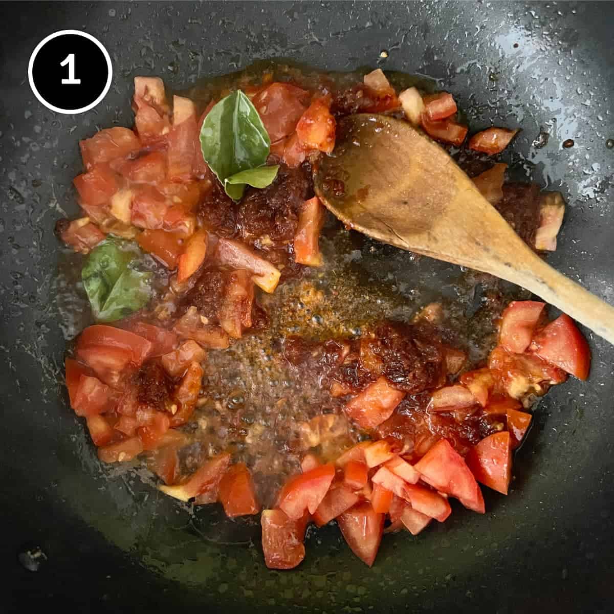 Stir frying tomatoes, sambal sauce and lime leaves for Sambal Udang (Sambal Prawns)