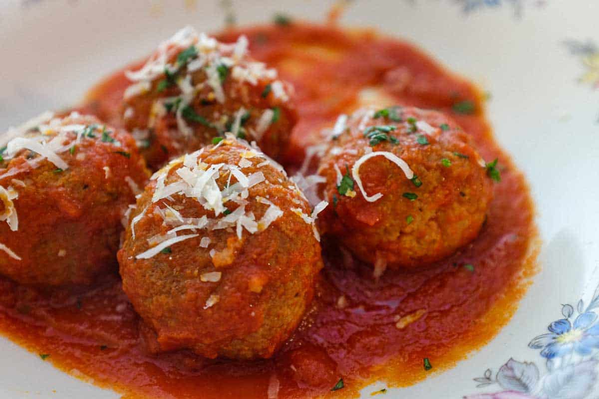 A plate of Pallotte - Cacio e Uova (Bread & Cheese balls) in a tomato sauce, garnished with a little Parmigiano cheese.