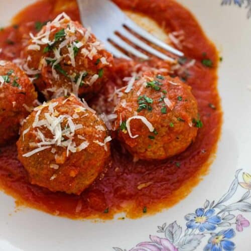 A plate of Pallotte - Cacio e Uova (Bread & Cheese balls) in a tomato sauce, garnished with a little Parmigiano cheese.