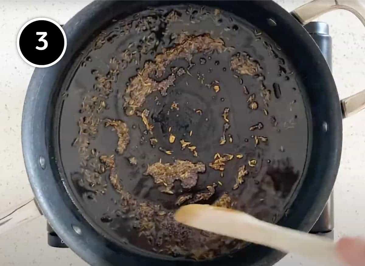 Stirring cumin seeds and mustard seeds for a Red Moong Dal Curry