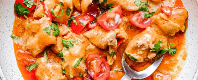 Thai peanut curry with chicken in a bowl, rich sauce and fresh herb garnish
