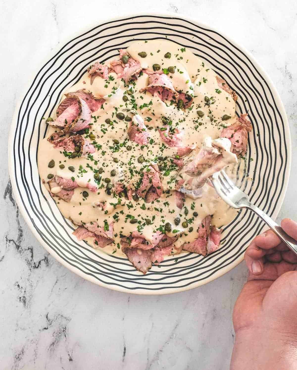 A fork taking some veal slices - Vitello Tonnato (Veal with Tuna & Anchovy Sauce