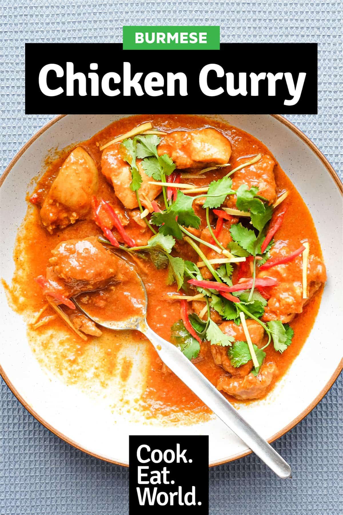 A bowl of Burmese chicken curry with fork and spoon