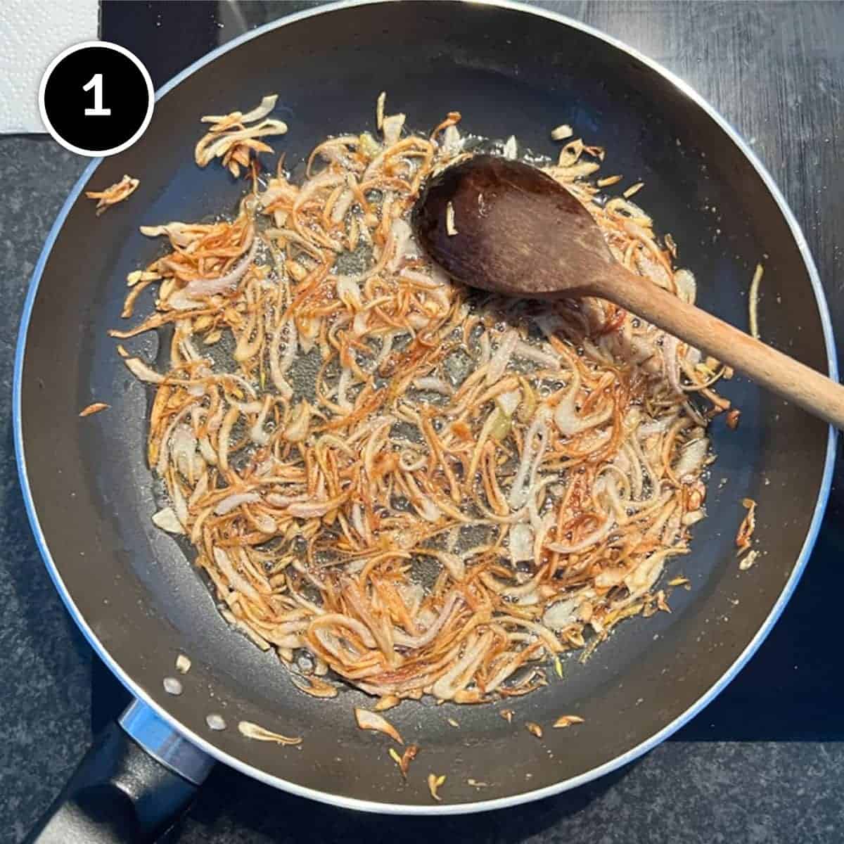 Frying shallots in a frying pan for a garnish to Thai Curry Noodle Soup with Salmon