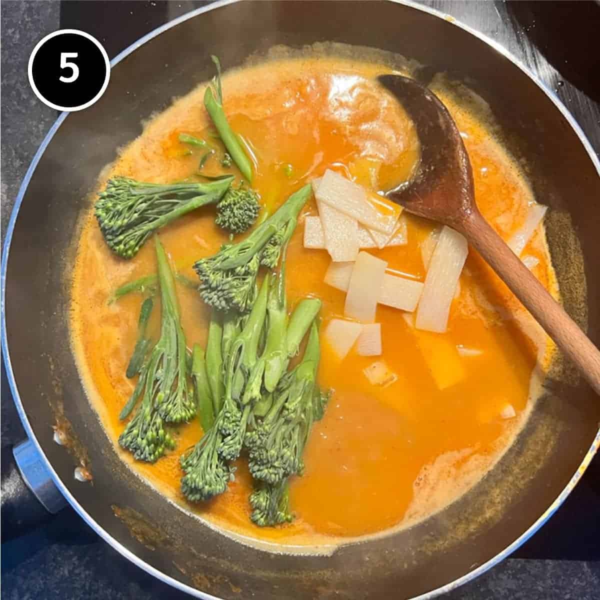 Cooking the broccolini and bamboo slices in the broth for Thai Curry Noodle Soup with Salmon