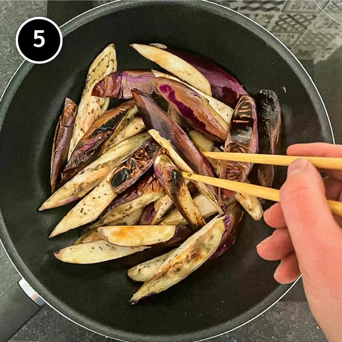 Frying eggplant in a wok until lightly charred.